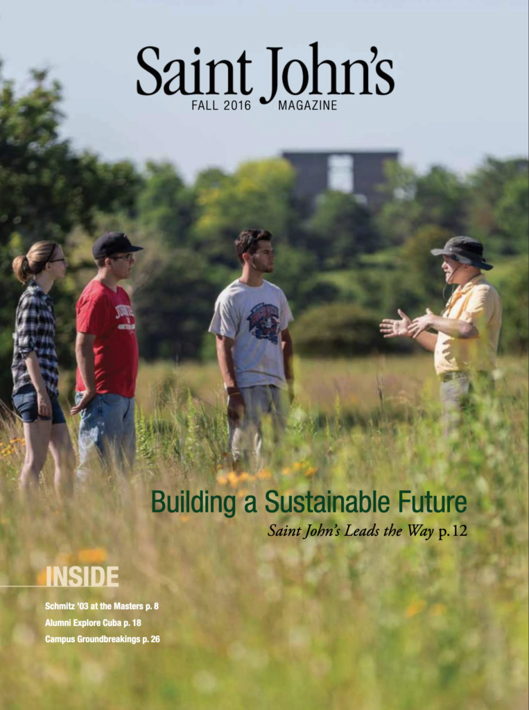 Four people stand in a grassy field having a conversation. One person is gesturing with outstretched arms. The background shows trees and a distant building. The text on the image reads "Building a Sustainable Future" under the magazine title "Saint John's.